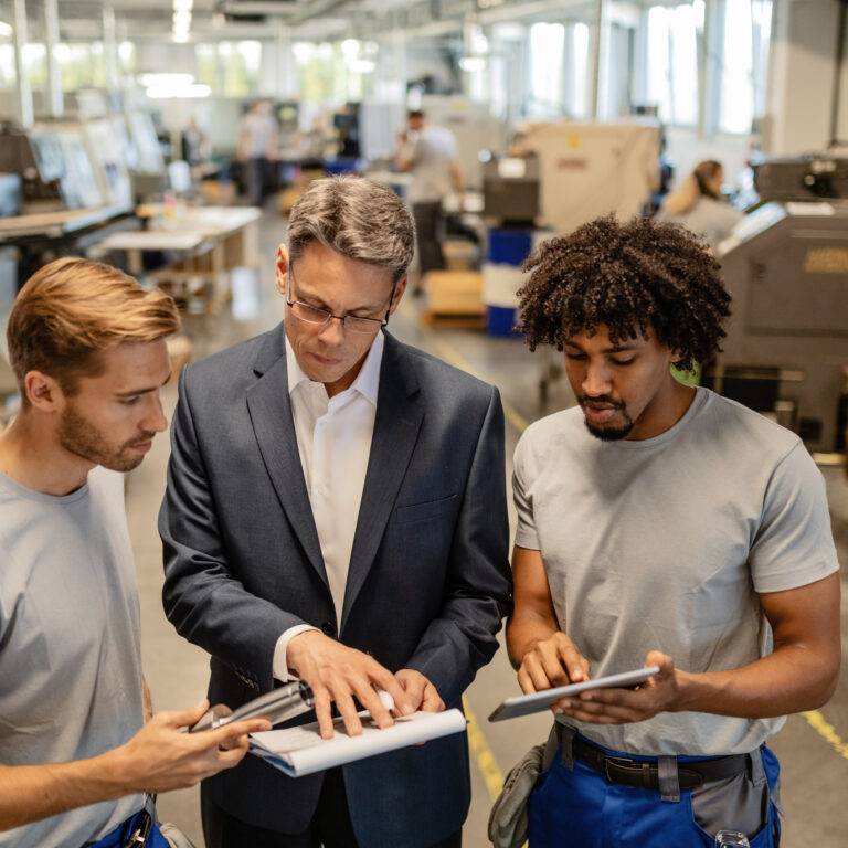 Young metal workers cooperating with their manager while reading